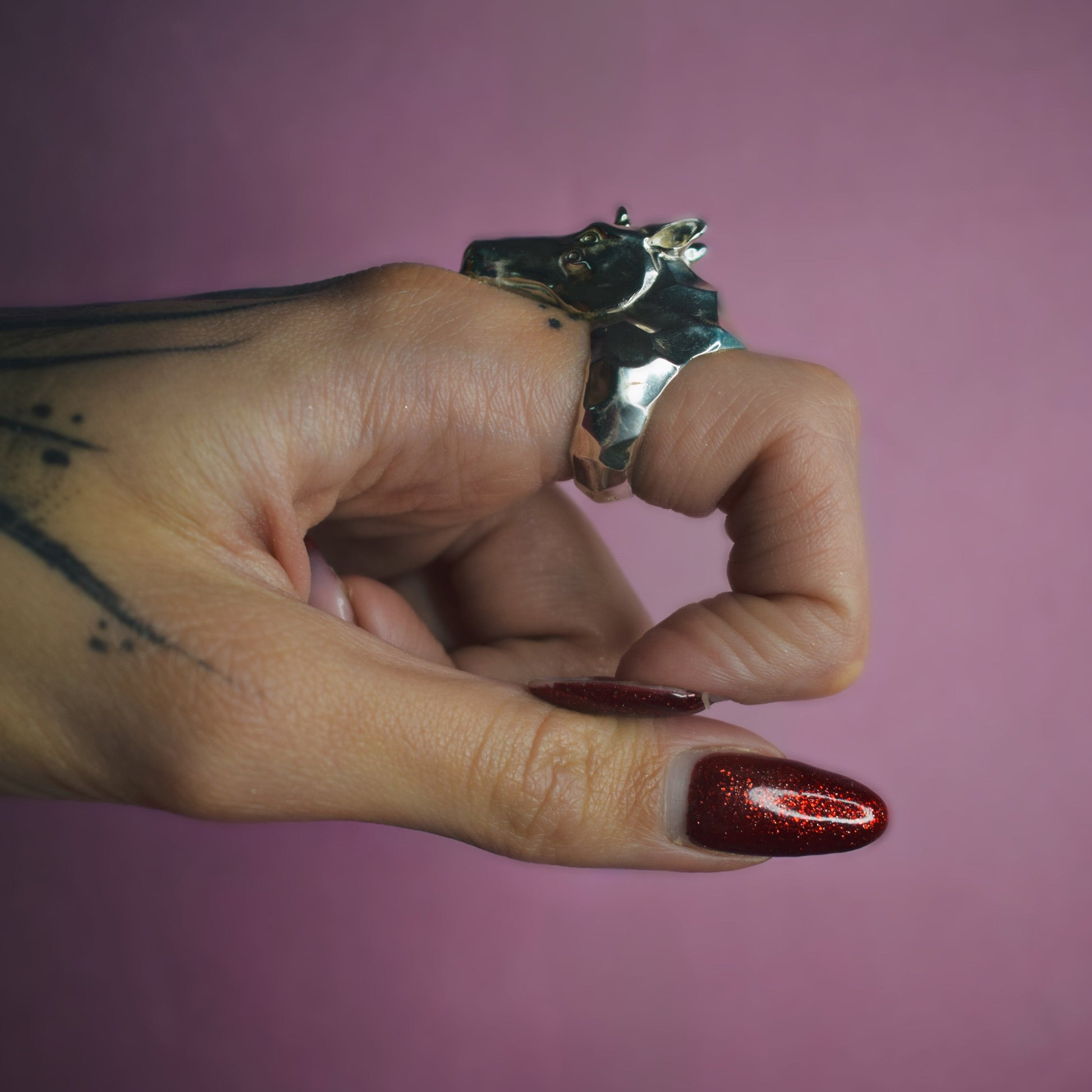 Hand with a ring on a pink background
